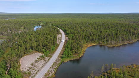 AERIAL:-RV-driving-in-middle-of-arctic-wetlands-of-Lapland,-summer-day-in-Finland