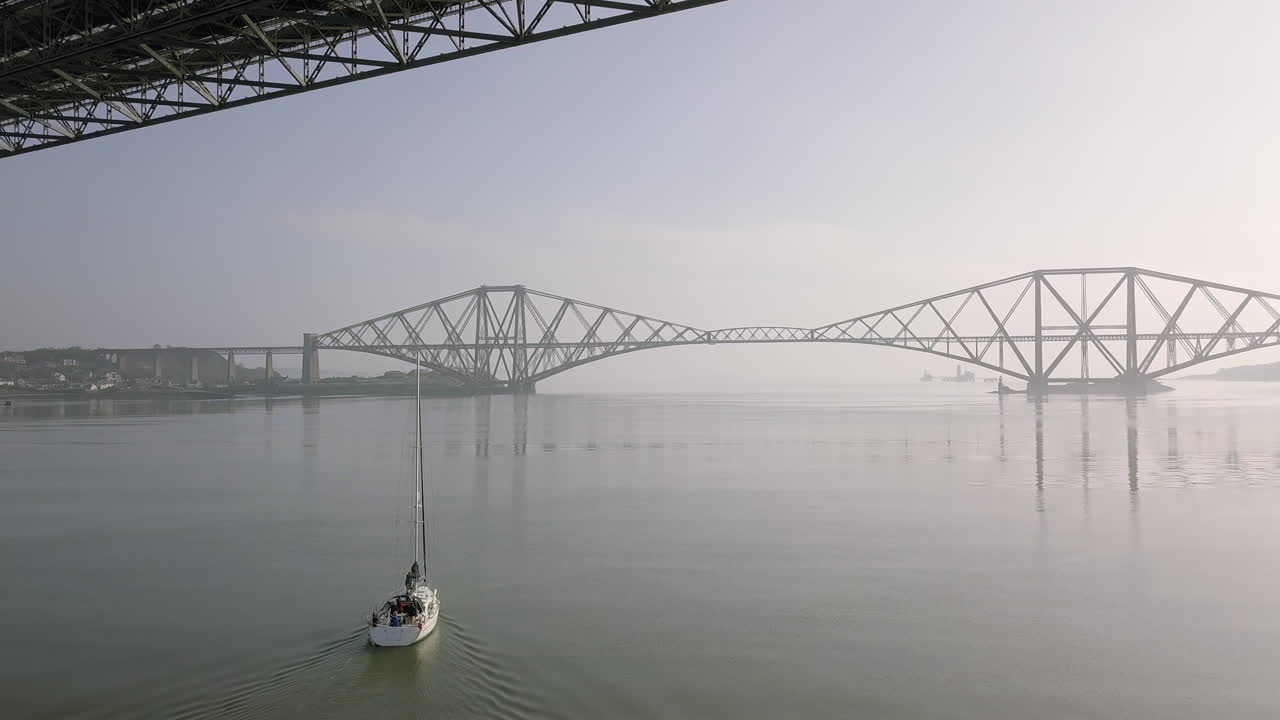 스코틀랜드 서부 로디안의 화창한 날 사우스 퀸스페리의 오래된 네 번째 도로 다리 아래를 여행하는 범선의 항공 영상
