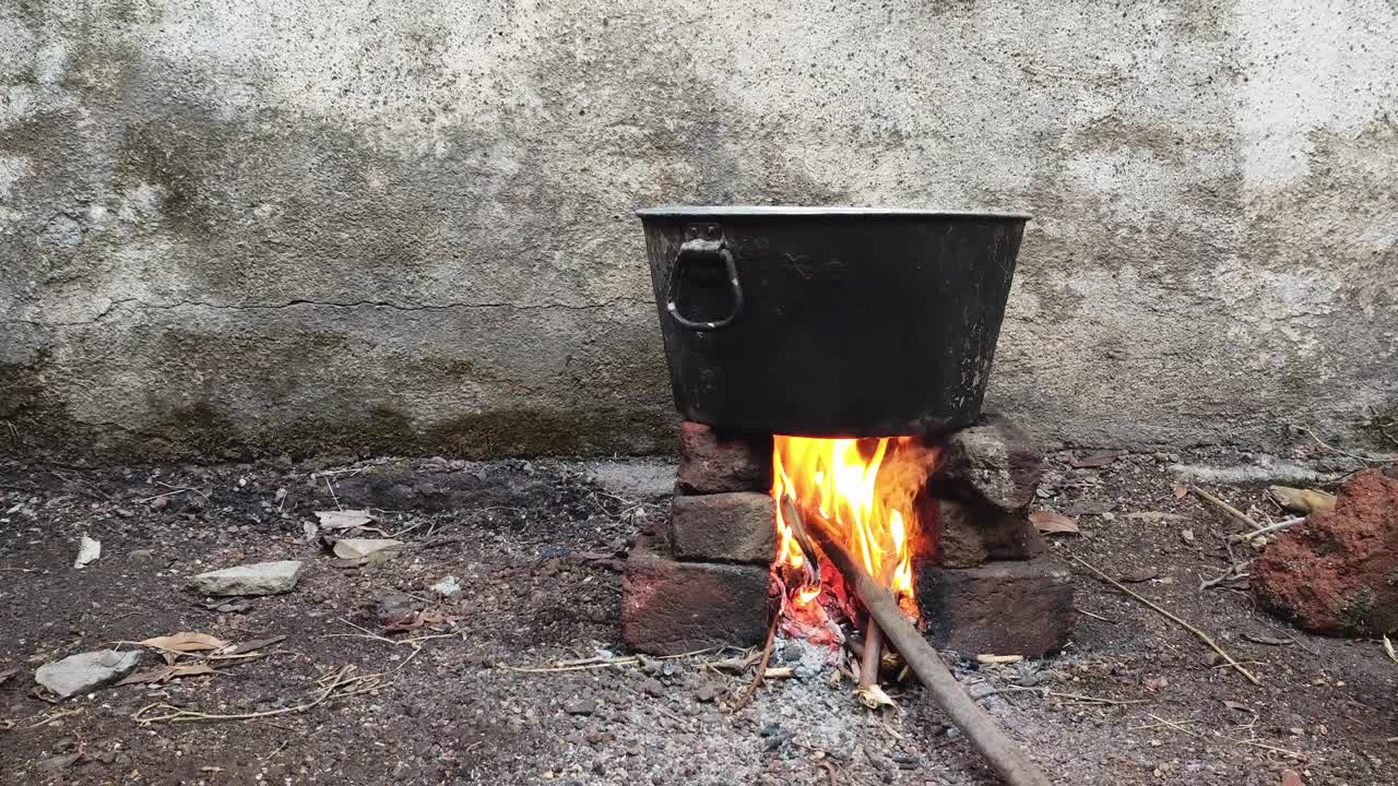 A traditional food pot on a chulha in an open space in Maharashtra, India. Flames from burning wood heat the vessel, creating a rustic cooking scene rooted in rural Indian culture and simplicity