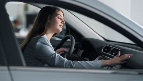 Mujer-Elegante-Con-Traje-Sentado-Detrás-Del-Volante-Acaricia-El-Salpicadero-Del-Coche-Y-Sonríe