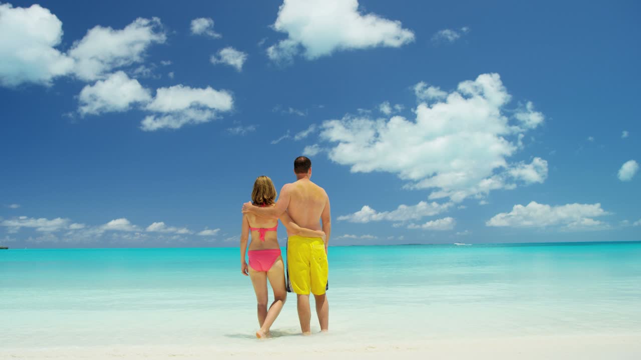 pareja caucásica en una playa de arena blanca en traje de baño