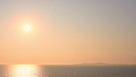 evocative shot of bright sun reflecting over sea with mountain in background