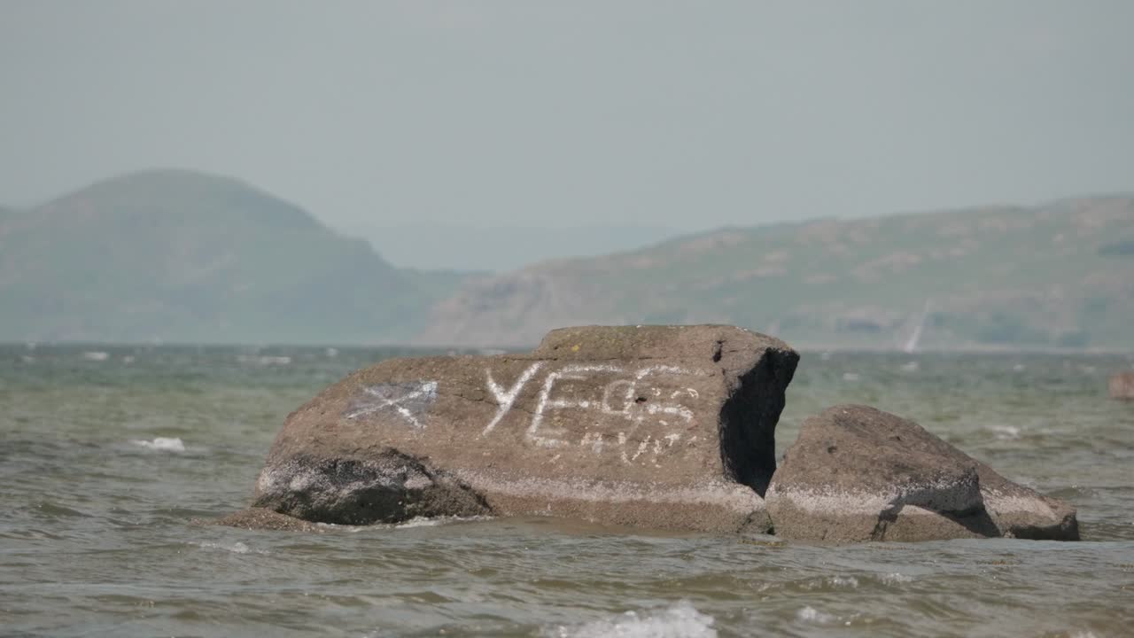 National flag and YES painted on sea rock off coastal Scotland