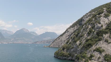 Drone-shot-of-Lake-Garda-with-small-sailing-boats-on-the-lake-in-the-background-are-mountains-on-a-sunny-day