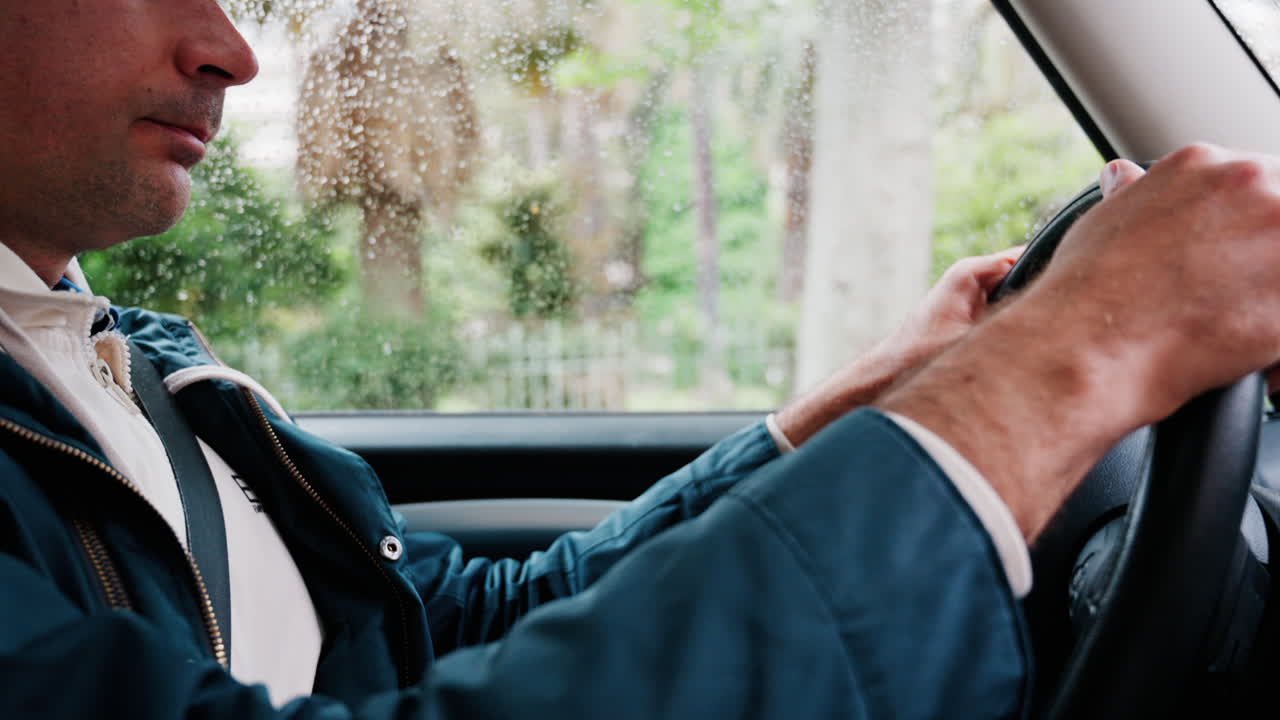 Close up of a man driving a car on the road in the rain