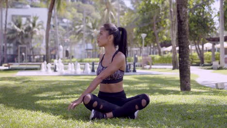 Asian-relaxed-woman-sitting-with-crossed-legs-in-park