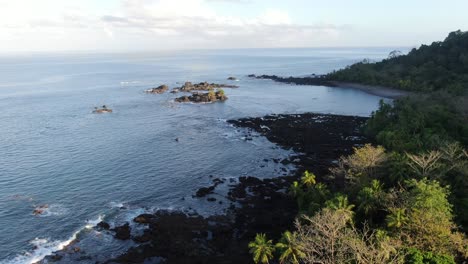 Costa-Rica-beach-drone-view-showing-sea,-shore-and-palm-tree-forest-in-Corcovado-National-Park-on-Osa-Peninsula-on-a-sunny-day-in-the-pacific-ocean-early-in-the-morning