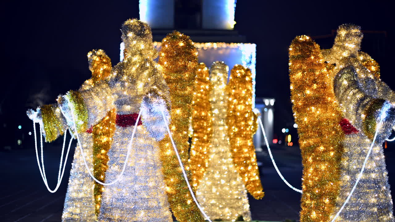 This vibrant display features illuminated angels in the park, showcasing bright lights and holiday spirit during the festive season. The scene captures the essence of celebration at night