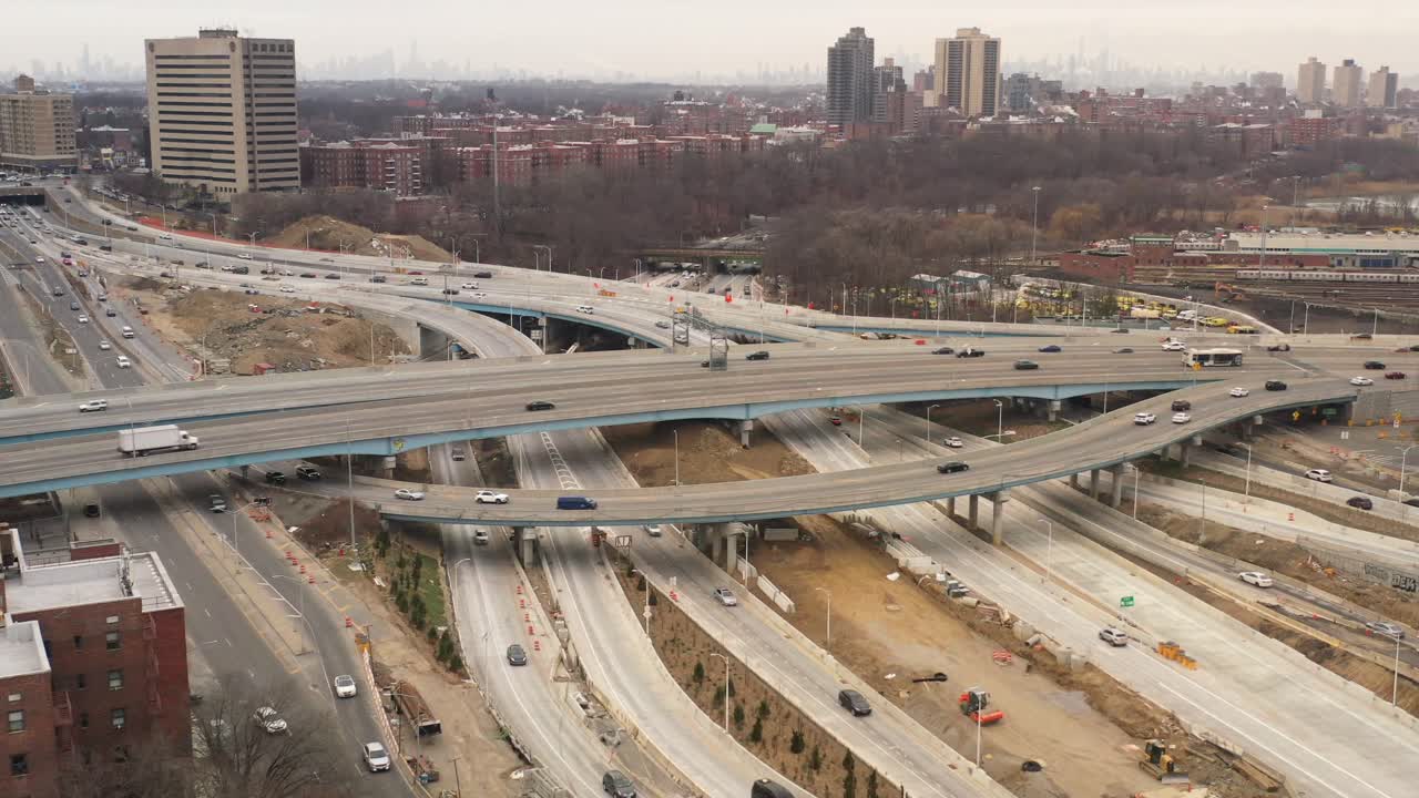 An aerial view of a highway intersection with moving urban traffic on a cloudy Sunday afternoon in winter. The drone camera dolly out, tilt up and pan left showing the complicated roads.