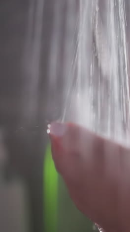 la mujer está de pie bajo una lluvia constante de agua caliente. la dama mueve las manos bajo el rociado de agua calurosa en la ducha. las manos de la mujer se bañan en el arroyo que fluye
