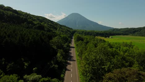 aerial follows japanese highway asphalted route to mount yotei's crater and surrounding alpine flora in hokkaido