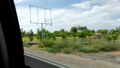 Looking-out-of-car-window-at-rural-farming-landscape-view-of-crop-fields-and-rice-paddies-in-the-remote-districts-of-Timor-Leste,-Southeast-Asia