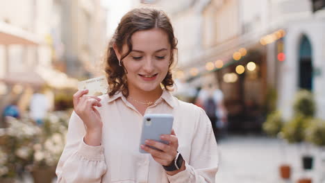 young woman using credit bank card smartphone while transferring money, purchases online shopping