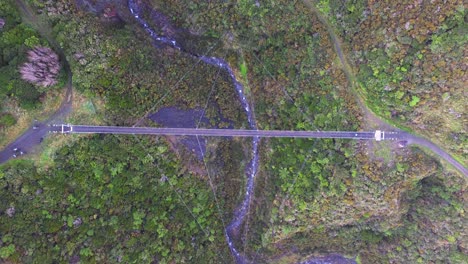 vista a vista de pájaro sobre un puente oscilante mientras los ciclistas lo cruzan