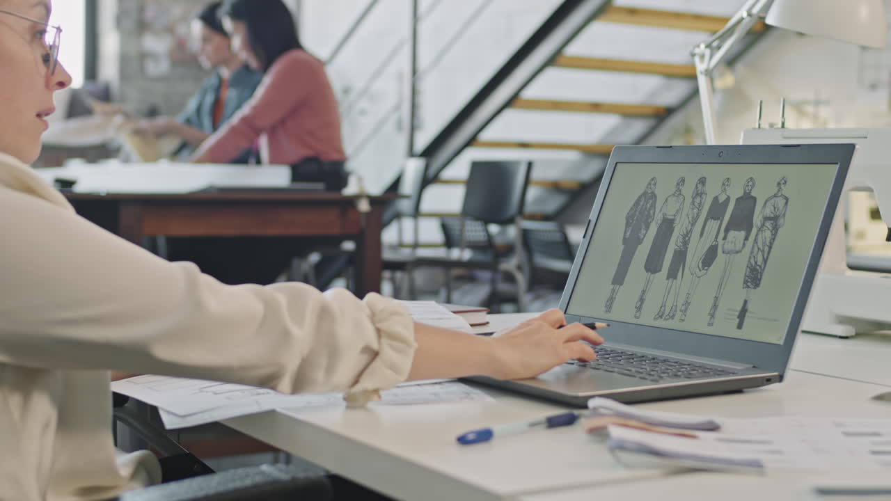 Woman Looking at Fashion Sketches and Working on Collection
