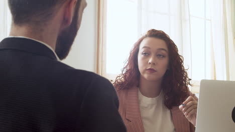 young businesswoman debating with her male colleague while looking at laptop computer