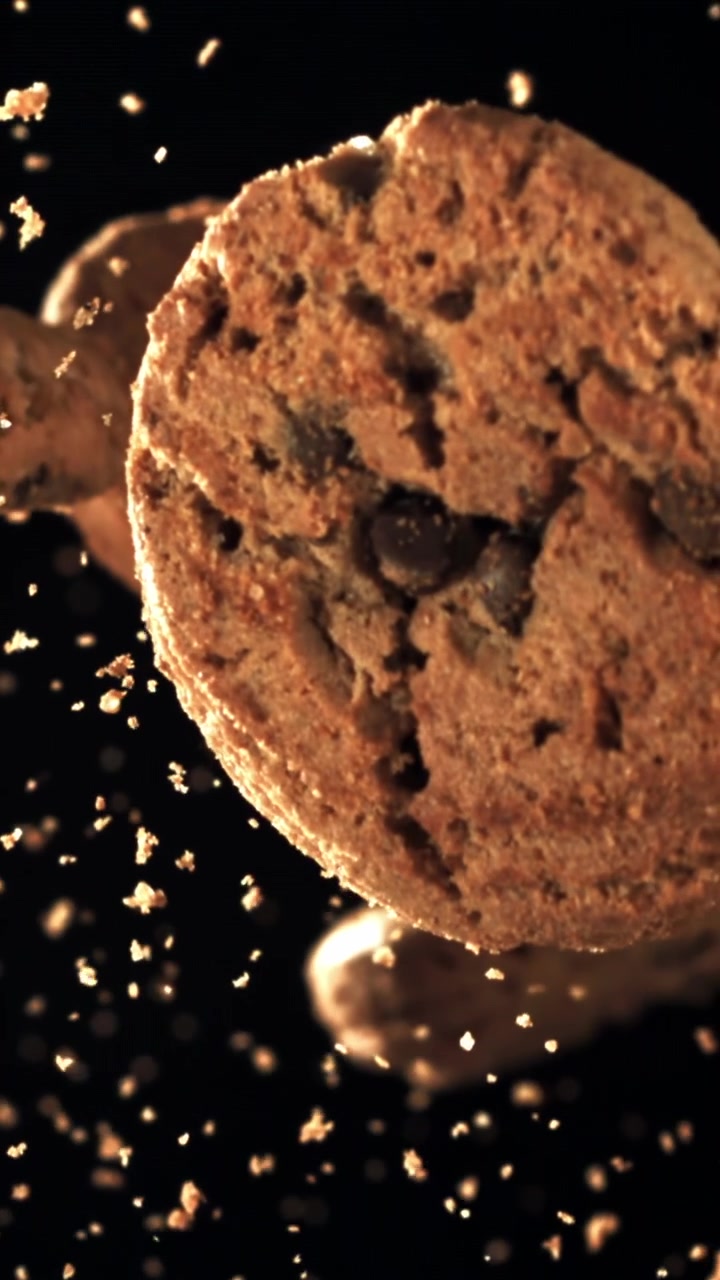 Chocolate Chip Cookies Floating with Crumbs on Black Background in Slow Motion