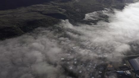 aerial above reydarfjordur village covered in low clouds in iceland