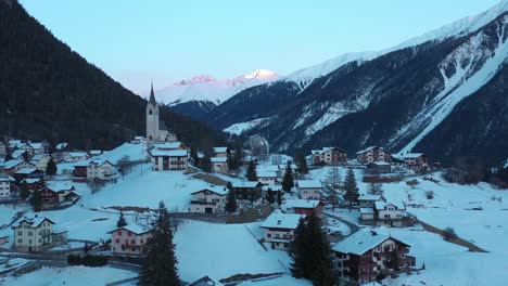 Excelente-Vista-Aérea-De-La-Invernal-Ciudad-Montañosa-De-Schmitten,-Suiza-Al-Atardecer