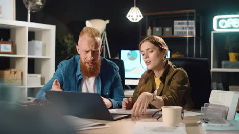 Young-business-couple-arguing-in-night-office.-Two-hipsters-discussing-project