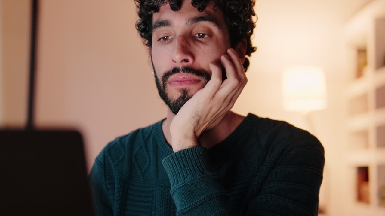 Thoughtful Gay Man Working From Home on Laptop