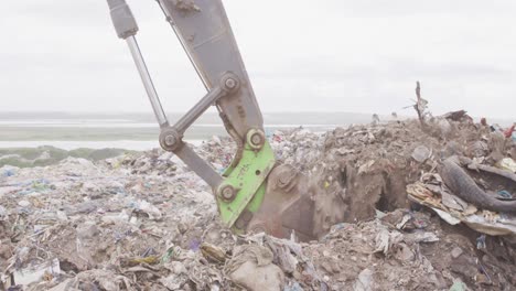 excavador limpiando basura apilada en un vertedero lleno de basura