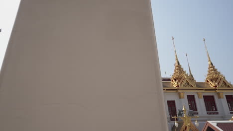 slide right shot to reveal a popular tourist destination white and gold buddhist temple in the city of bangkok in thailand on a very sunny and hot day
