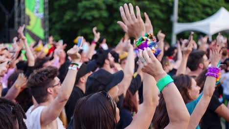 young music fans gathered at summer festival, dancing passionately and raising arms with infectious joy, celebrating live music performance with collective enthusiasm and youthful energy