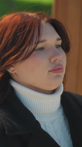 primer plano de una mujer sentada en un columpio de madera, su cabello soplando suavemente en el viento, con la luz del sol reflejándose suavmente en su rostro en medio de la exuberante vegetación