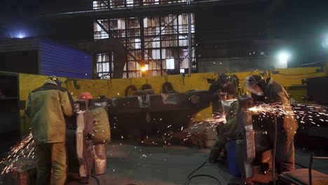 industrial workers welding and fabricating metal parts at night