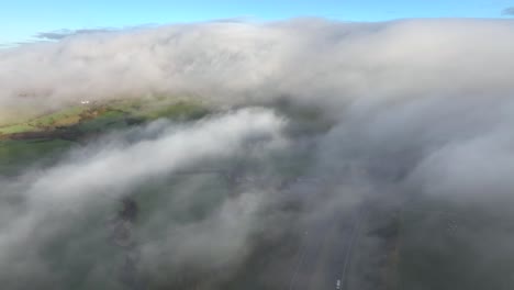 flying above thick mist with pan up revealing thick cloud bank covering large hill