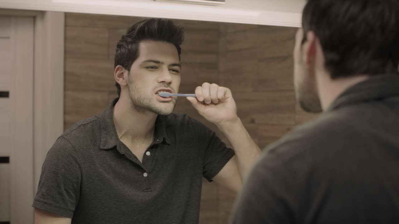Concentrated man cleaning teeth in bathroom. Closeup male person brushing teeth