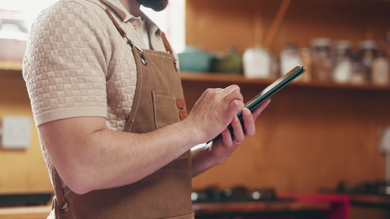 A person wearing an apron uses a tablet indoors