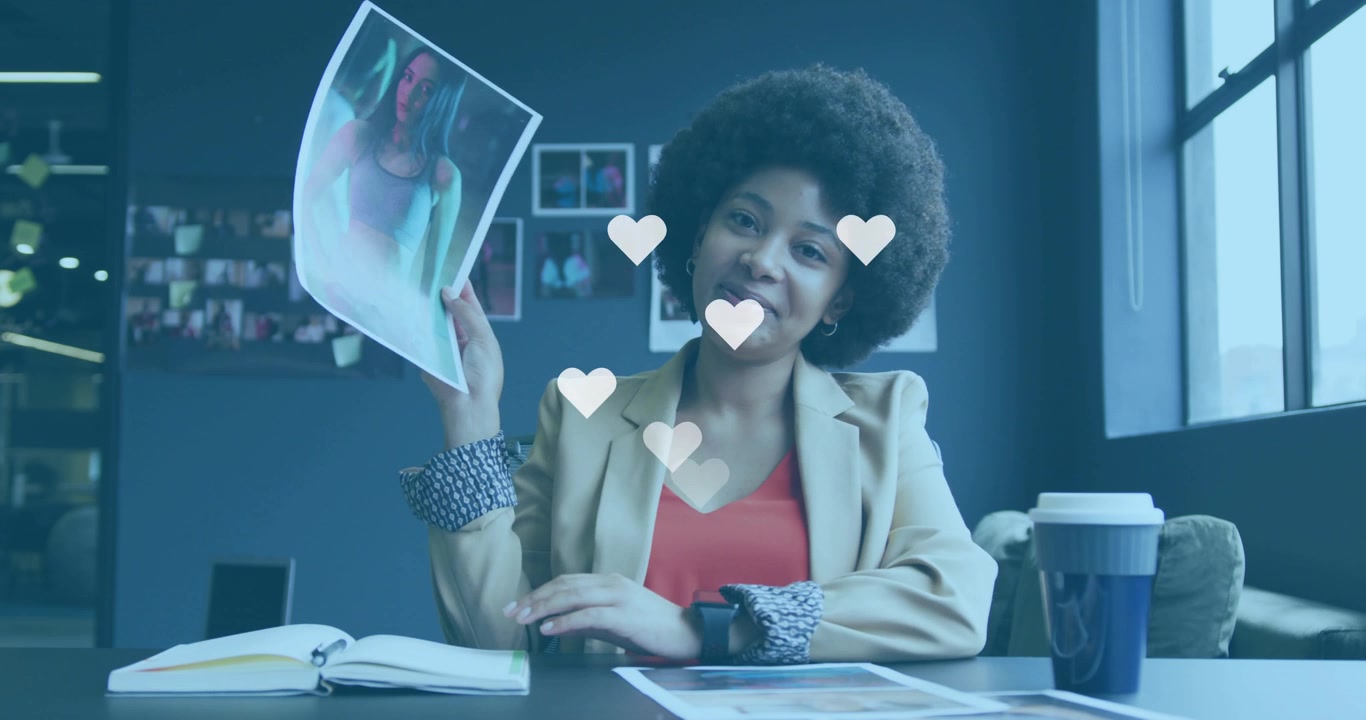 Vertical video: Smiling, sparking animated hearts, woman lifting print and pointing, showing design
