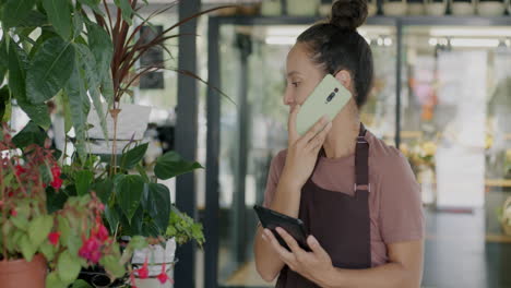 woman florist talking on phone and using tablet in shop
