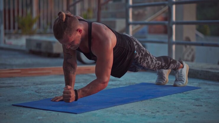 Muscular Man Performing Plank Exercises on Yoga Mat Outdoors