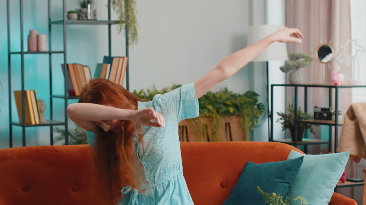 트렌디하고 즐거운 긍정적인 여성이 춤을 추고 리 ⁇ 에 따라 움직이며 현대 가정에서  ⁇  댄스 제스처를 만 ⁇ 니다.