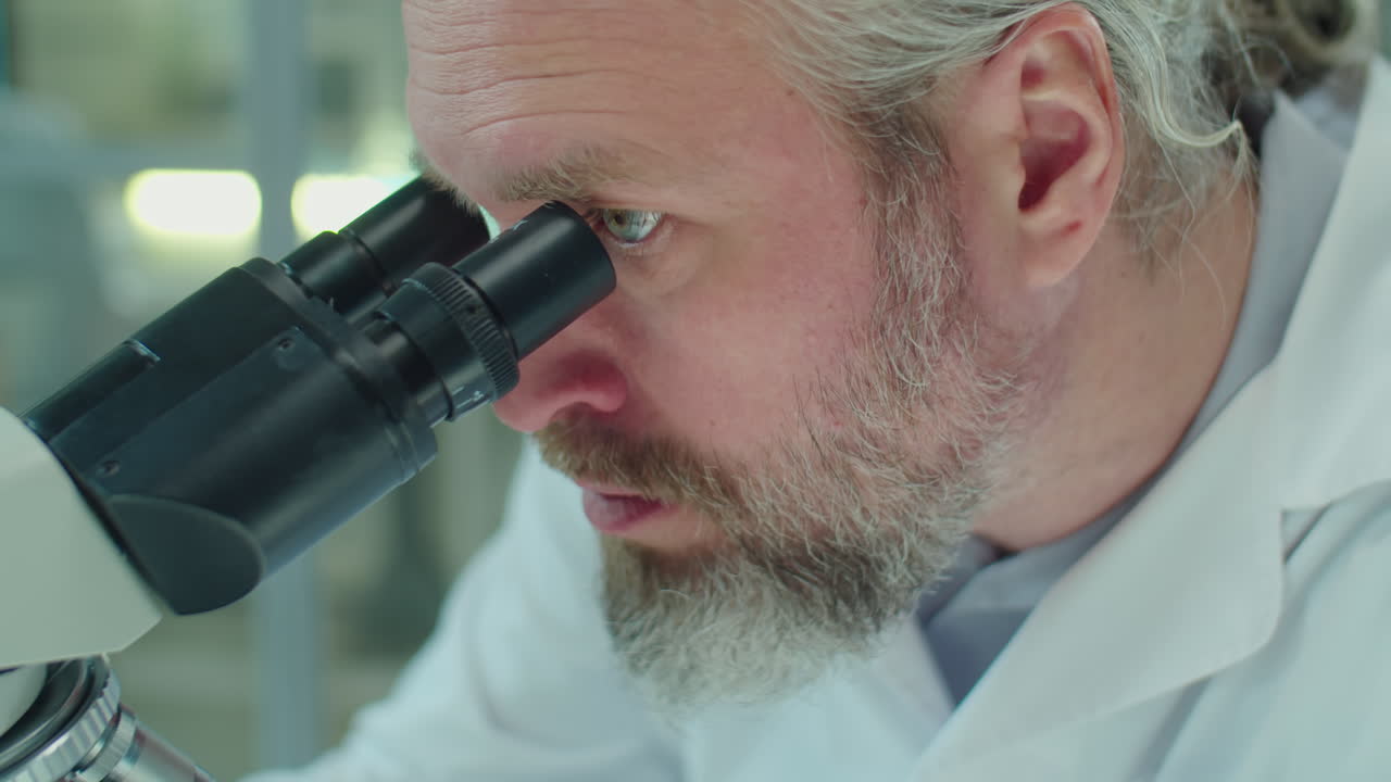 Mature Scientist Looking through Microscope