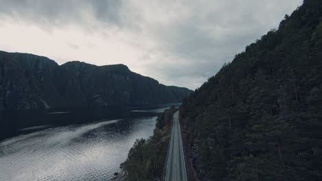 Paisaje-Montañoso-Con-Agua-De-Lago-Y-Carretera-Asfaltada,-Vista-Aérea-De-Drones