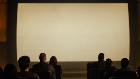 audience members enjoying a film on a large screen in a darkened cinema, immersed in the entertainment experience