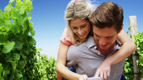 Man-giving-woman-piggy-back-in-vineyard