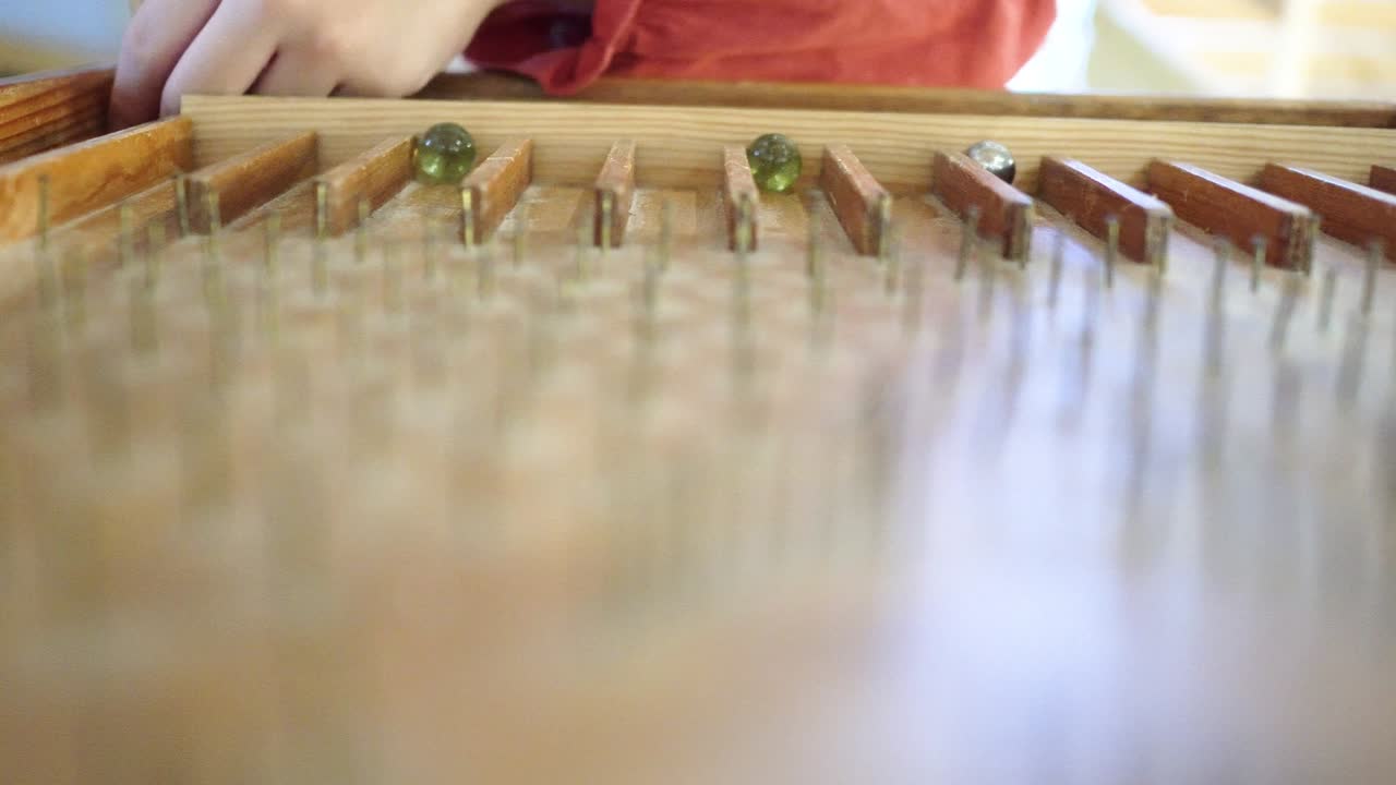 cerca de la mesa de pinball hecha de madera. las cuentas de vidrio rodan hacia abajo en la mesa de flipper. un juego jugado por un niño. el tema está a la izquierda.