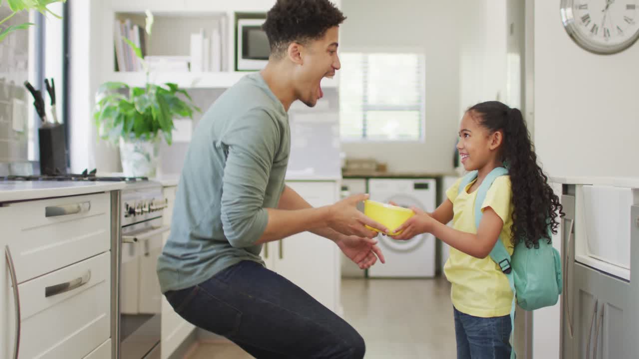 padre y hija biraciales felices abrazándose en la cocina
