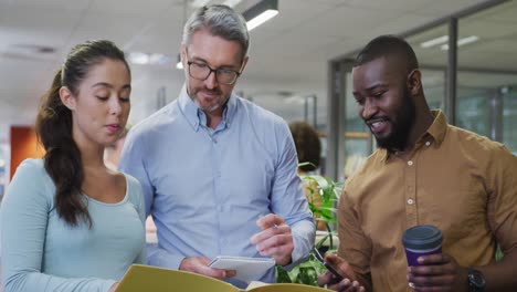 Diverse-male-and-female-business-colleagues-talking-and-holding-documents