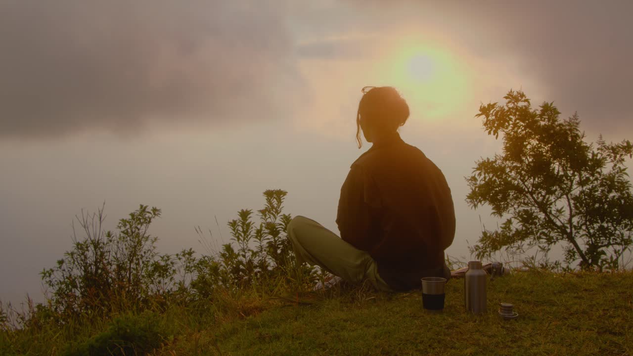 Woman meditating at sunrise on a mountaintop