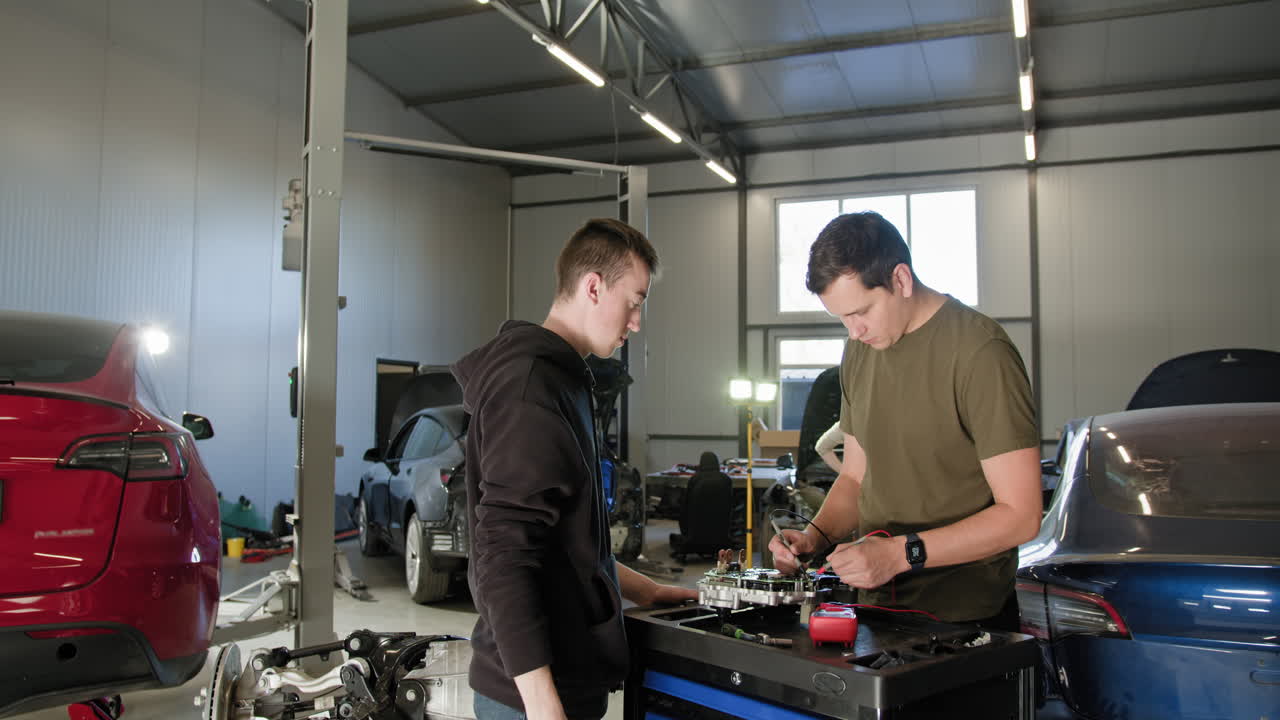 Two mechanics working on an electric vehicle in a repair shop
