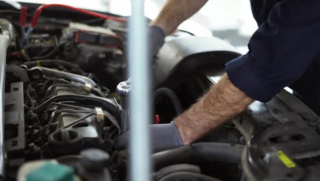 mecánico de automóviles usando llave inglesa para reparar el motor en un servicio de automóviles, de cerca
