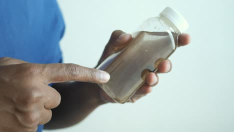 a man pointing to a bottle of dirty water