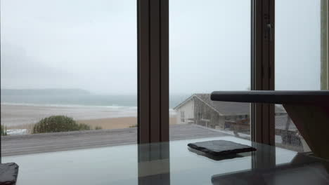 raindrops falling against glass doors in slow motion with a coffee table in foreground