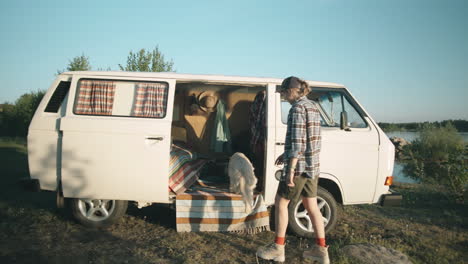 woman and dog camping in travel trailer by lake